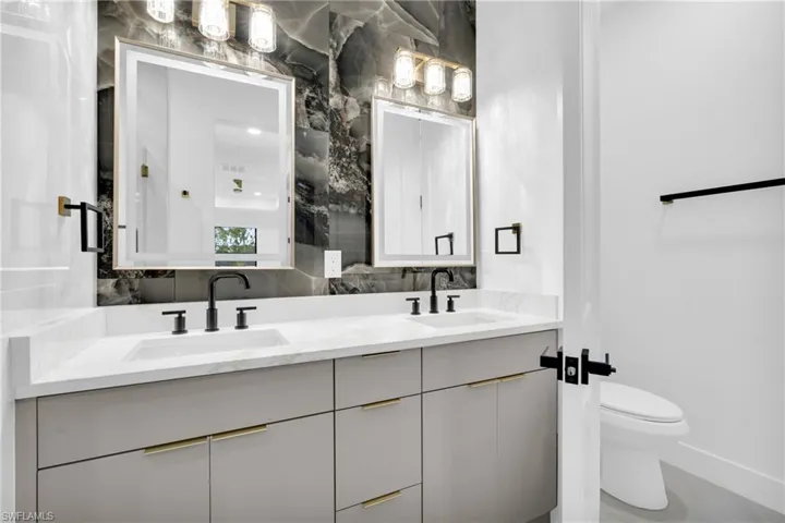 Full bath featuring double vanity and tasteful backsplash