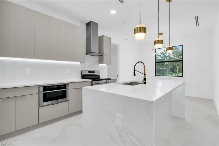 Kitchen with wall chimney range hood, stainless steel appliances, modern cabinets, gray cabinets, and recessed lighting
