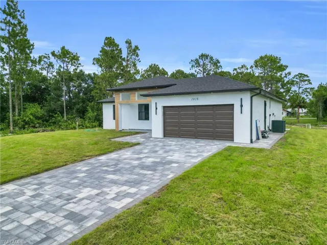 View of front of house with stucco siding, a garage, a front yard, and decorative driveway