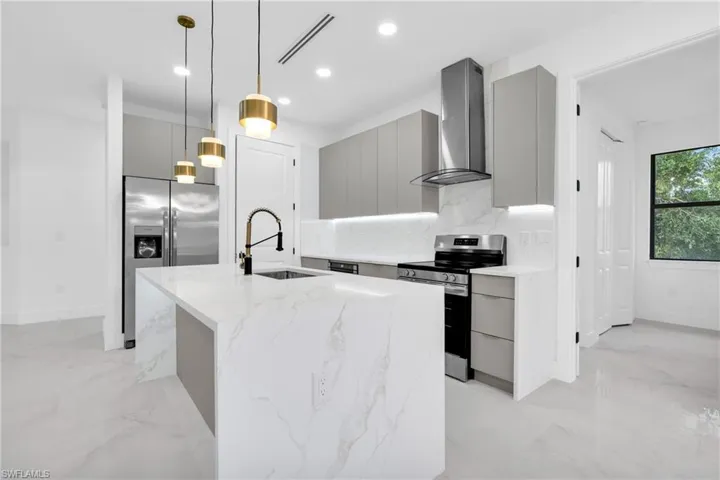 Kitchen with modern cabinets, appliances with stainless steel finishes, wall chimney range hood, gray cabinetry, and recessed lighting