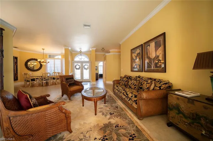 Living room featuring ornamental molding, french doors, and a chandelier