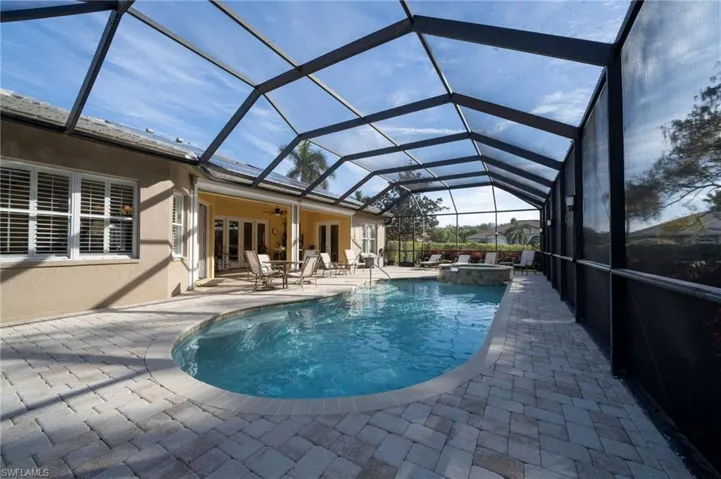 View of swimming pool featuring a lanai, ceiling fan, a patio, french doors, and an in ground hot tub