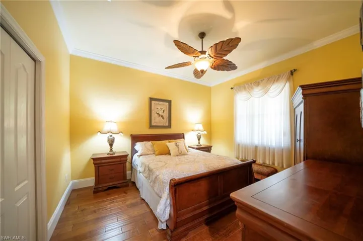 Bedroom with ceiling fan, ornamental molding, and dark hardwood / wood-style flooring