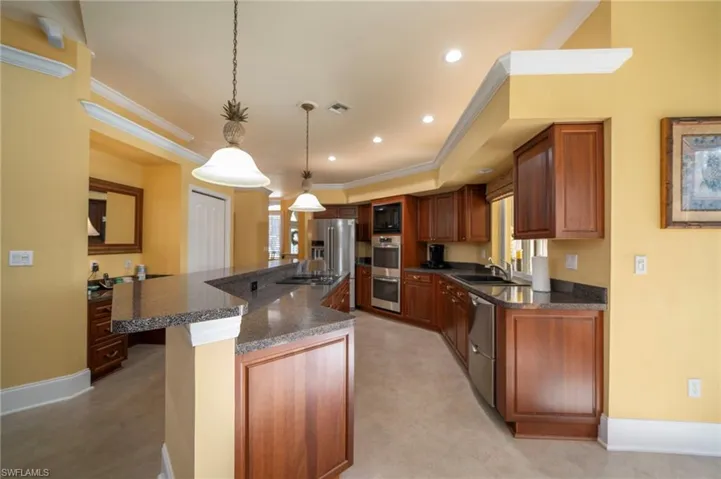 Kitchen with sink, decorative light fixtures, a center island, ornamental molding, and black appliances
