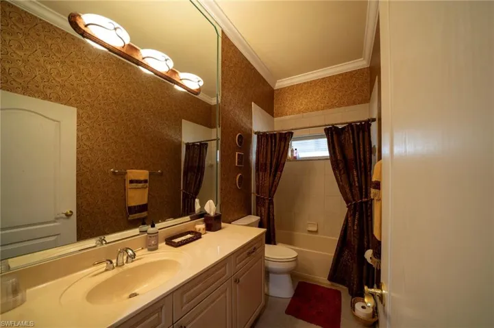 Full bathroom with shower / tub combo with curtain, ornamental molding, toilet, and vanity