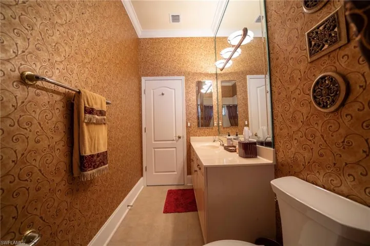 Bathroom with vanity, crown molding, and toilet