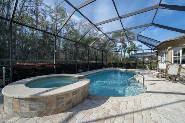 View of swimming pool with a patio, an in ground hot tub, and glass enclosure