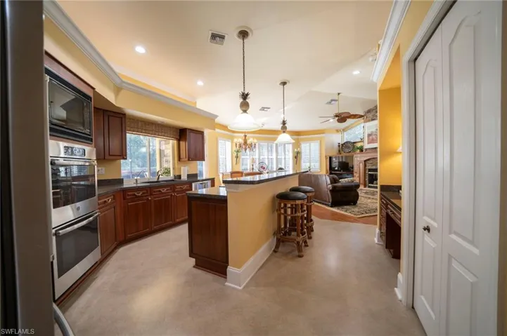 Kitchen with a center island, hanging light fixtures, a kitchen breakfast bar, stainless steel appliances, and ceiling fan with notable chandelier