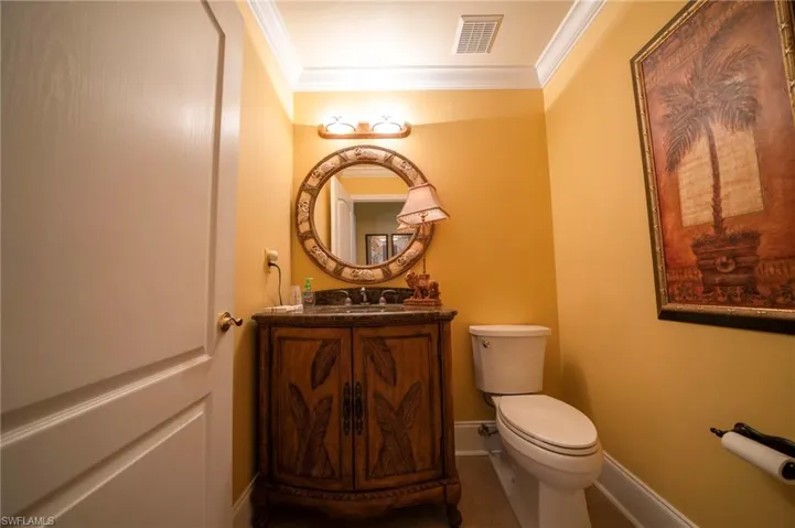 Bathroom with ornamental molding, vanity, and toilet