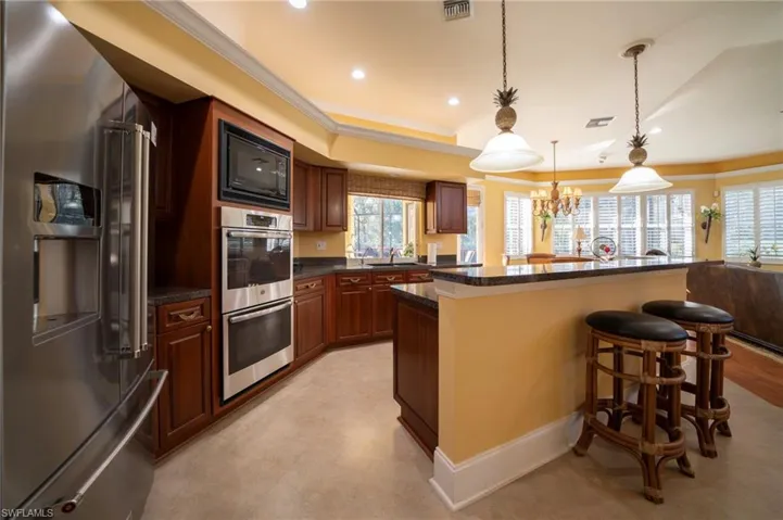 Kitchen with sink, decorative light fixtures, a center island, a kitchen breakfast bar, and stainless steel appliances