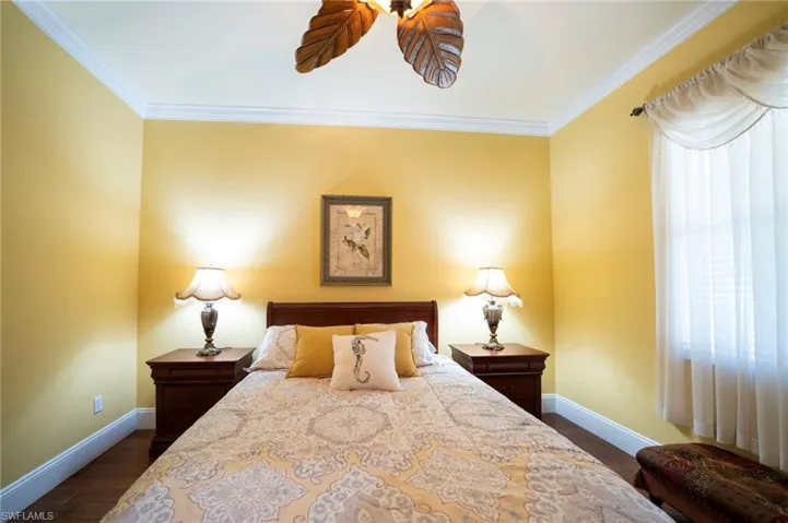 Bedroom with ornamental molding and dark wood-type flooring