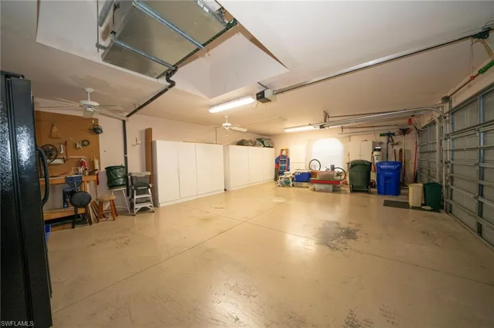 Garage featuring a garage door opener and black refrigerator