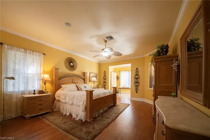Bedroom featuring hardwood / wood-style flooring, ceiling fan, and ornamental molding