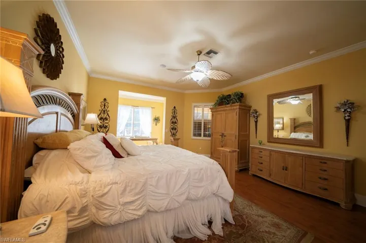 Bedroom with crown molding, dark wood-type flooring, and ceiling fan