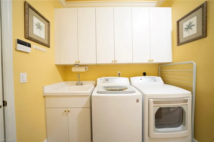 Laundry room with sink, crown molding, washer and clothes dryer, and cabinets