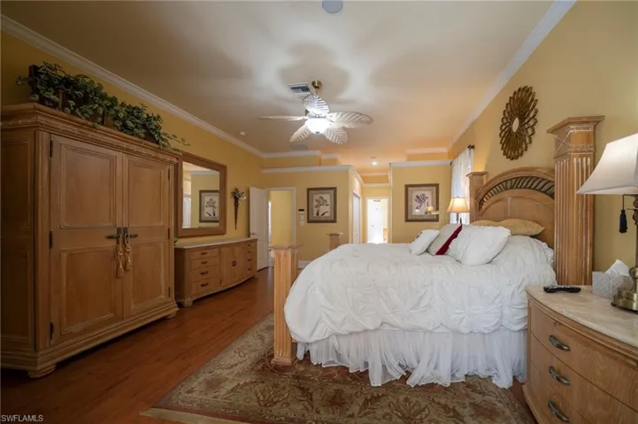 Bedroom with wood-type flooring, ornamental molding, and ceiling fan
