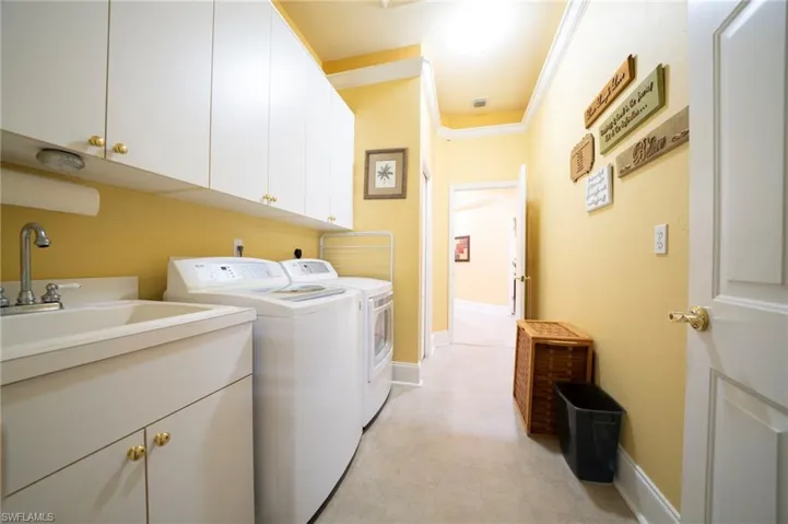 Washroom featuring cabinets, ornamental molding, sink, and washer and dryer