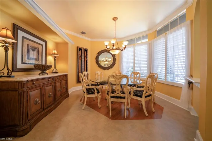 Dining area with light carpet, ornamental molding, and a chandelier