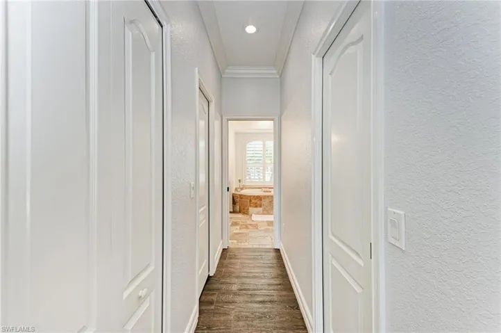Hall featuring a textured wall, crown molding, dark wood finished floors, and recessed lighting
