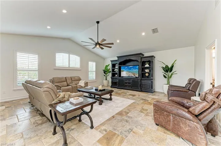 Living area with a ceiling fan, recessed lighting, and stone tile floors