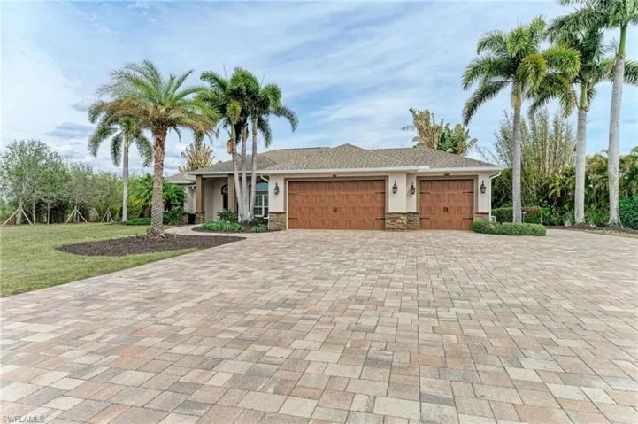 View of front of home featuring a garage, driveway, stucco siding, and stone siding