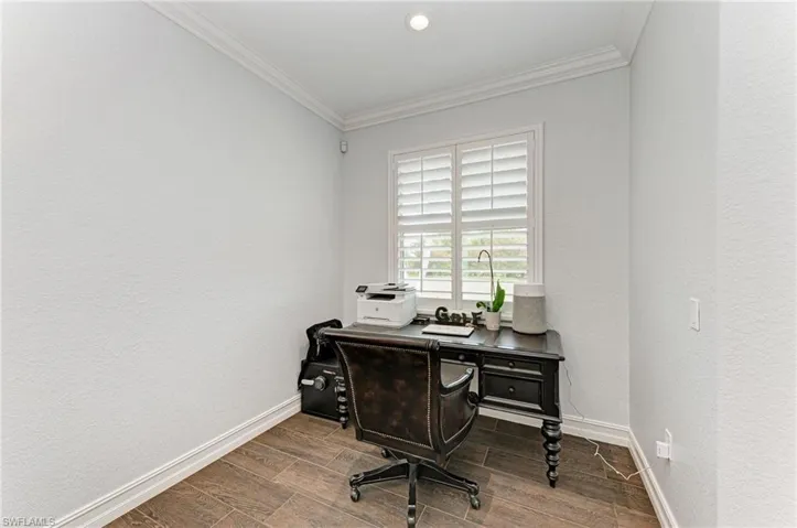 Home office featuring wood finish floors, a textured wall, and ornamental molding