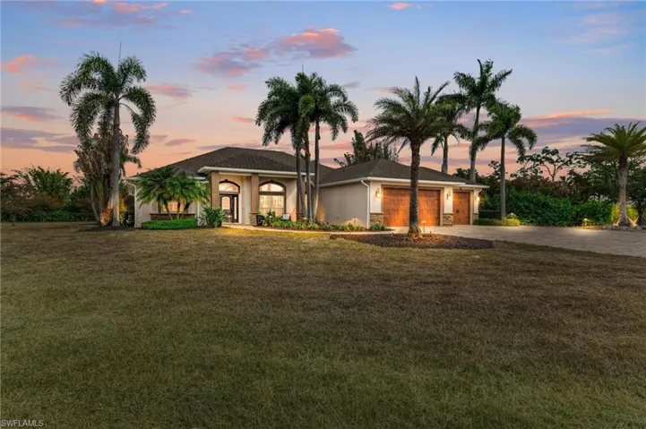 View of front facade with a front lawn, stucco siding, driveway, and an attached garage