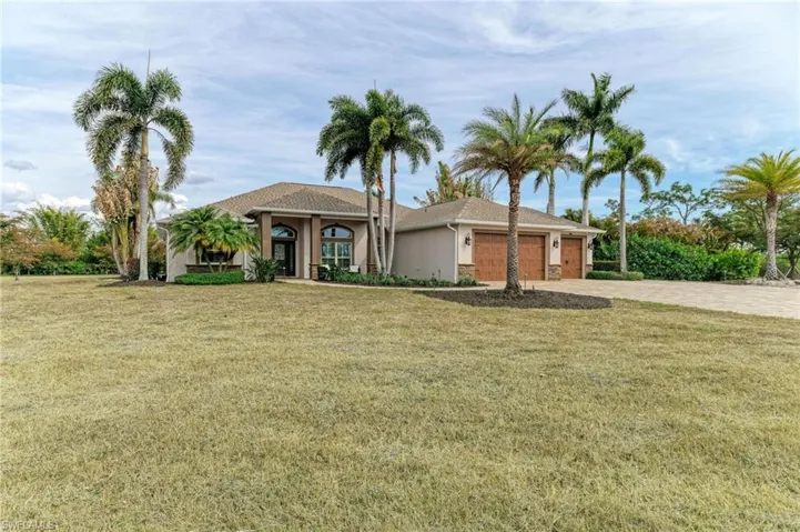 View of front of home with a front yard, an attached garage, stucco siding, and driveway