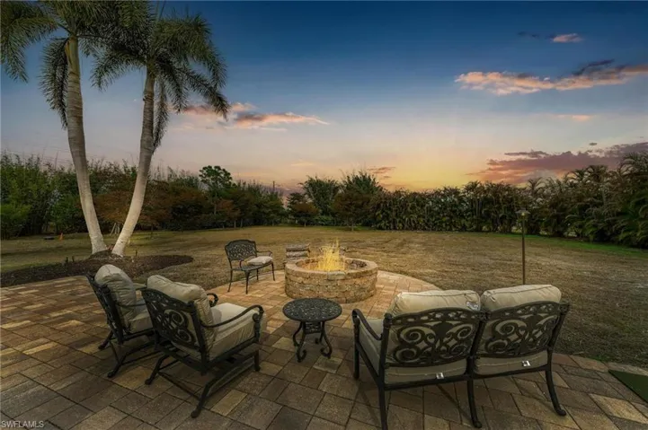 Patio terrace at dusk with a patio area, a yard, and an outdoor living space with a fire pit