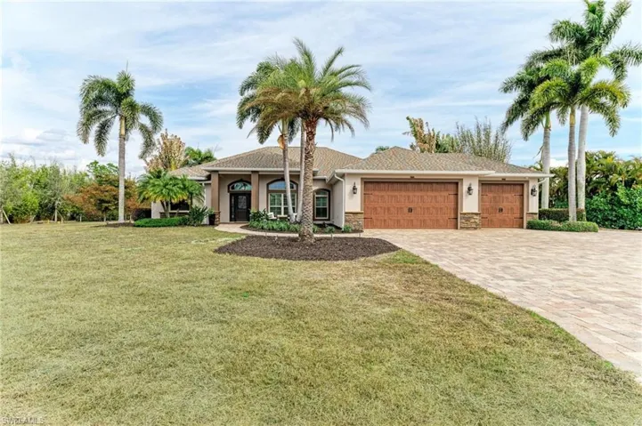 View of front of house featuring a garage, stucco siding, decorative driveway, a front lawn, and stone siding