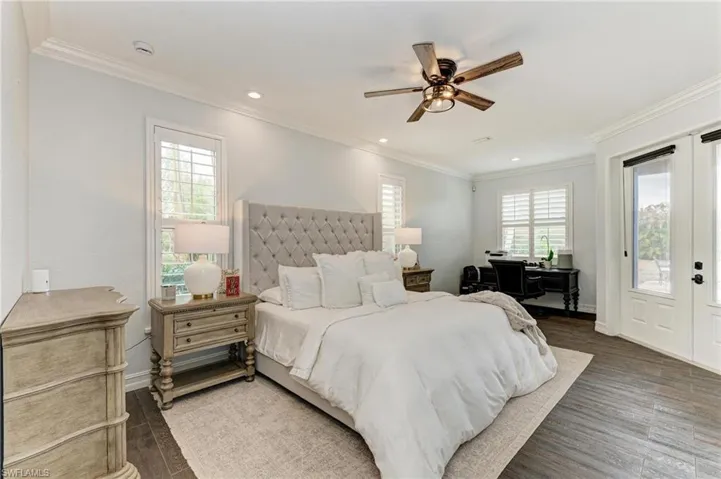 Bedroom featuring access to exterior, french doors, dark wood-type flooring, a ceiling fan, and multiple windows