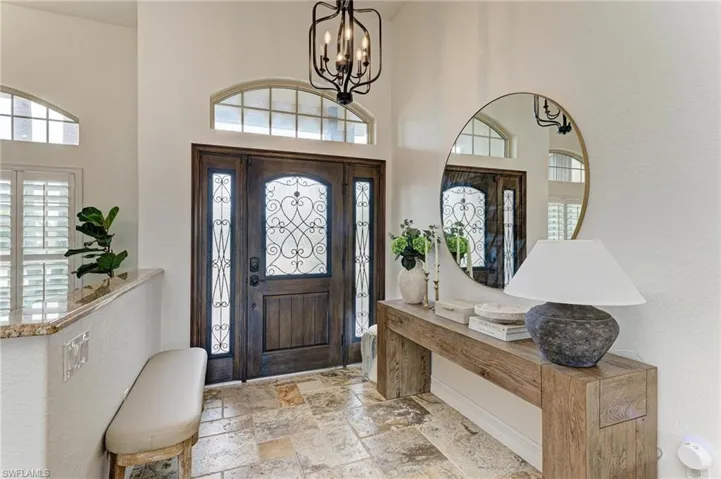 Entryway with stone tile flooring, a high ceiling, and hanging lights
