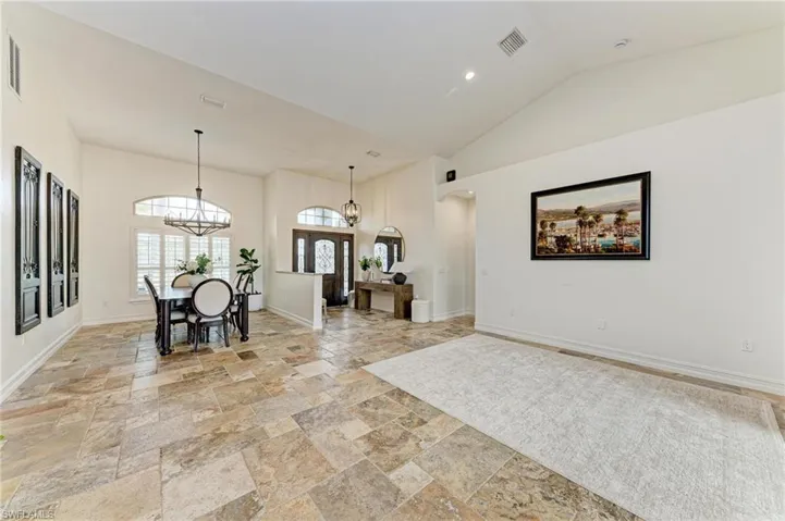 Foyer with arched walkways, stone tile floors, lofted ceiling, and recessed lighting