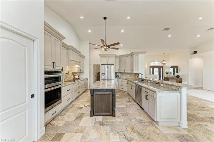 Kitchen featuring light stone counters, a kitchen bar, a peninsula, dual tone cabinets, and stainless steel appliances