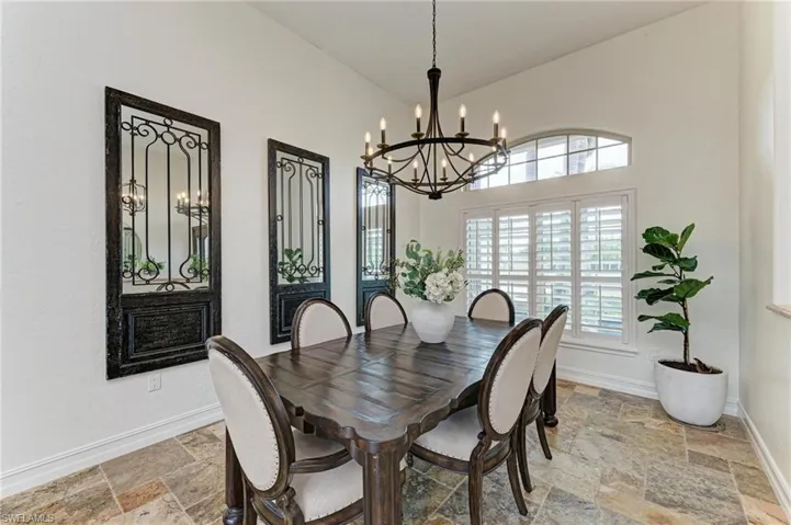 Dining room featuring stone tile flooring, a chandelier, and a high ceiling
