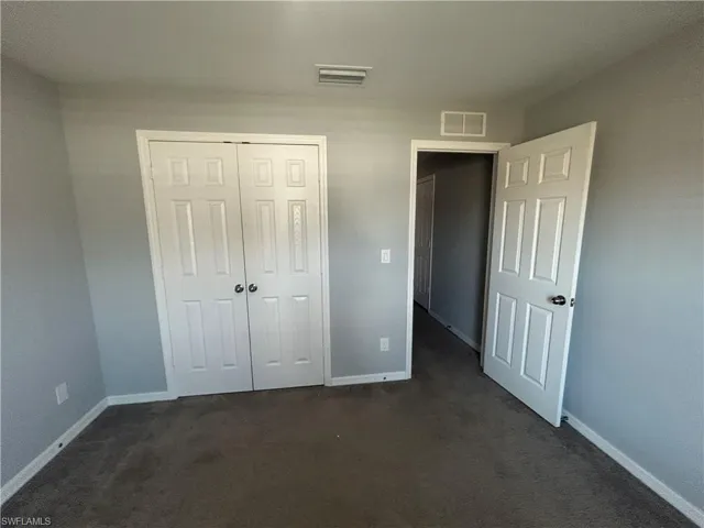 Unfurnished bedroom with dark colored carpet and a closet