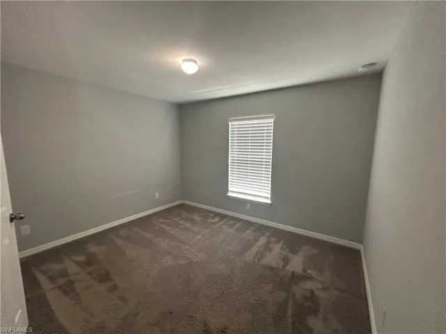 Spare room with dark colored carpet and baseboards