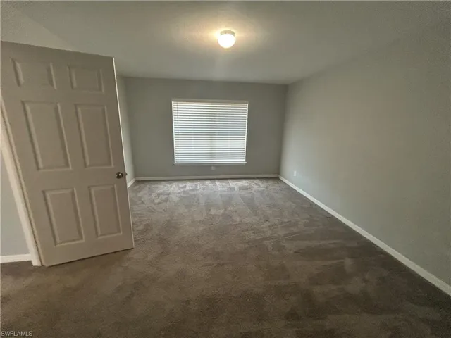 Carpeted empty room with baseboards