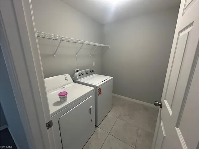 Laundry area with separate washer and dryer and light tile patterned floors