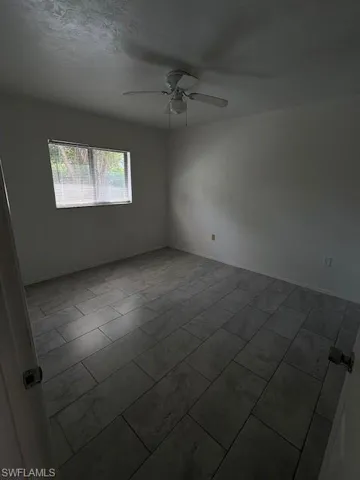 Empty room featuring ceiling fan and baseboards