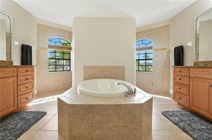 Full bathroom featuring vanity, a bath, plenty of natural light, and tile patterned floors