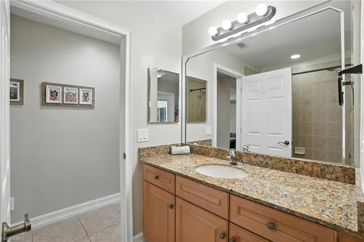 Bathroom with vanity, tile patterned flooring, and a tile shower