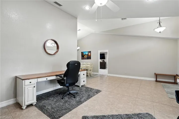 Office area with a ceiling fan, light tile patterned floors, and high vaulted ceiling