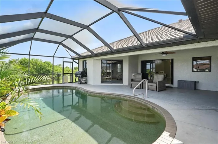 Outdoor pool with ceiling fan, a patio, a grill, and a lanai