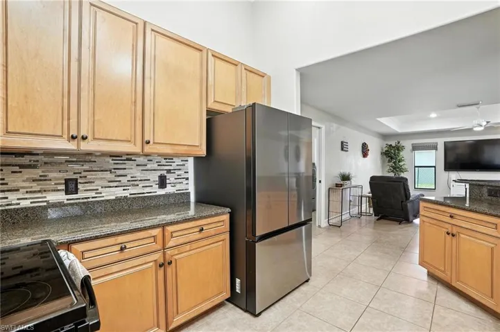 Kitchen featuring electric stove, freestanding refrigerator, backsplash, a raised ceiling, and open floor plan