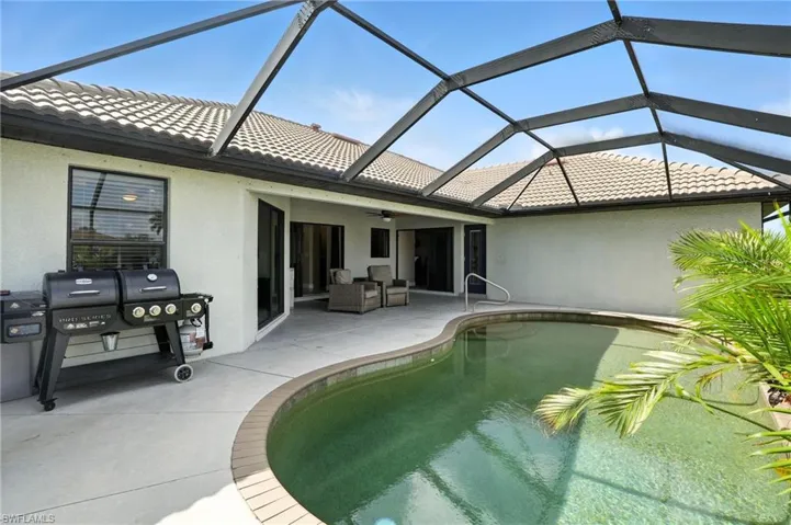 Outdoor pool with ceiling fan, a patio, glass enclosure, and a grill