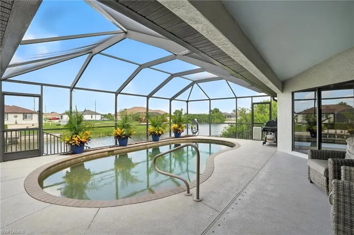 Outdoor pool featuring a water view, a patio area, glass enclosure, and a residential view