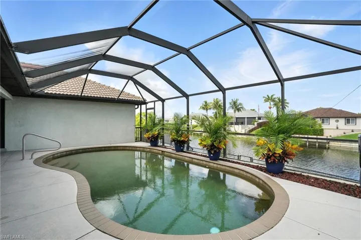 Swimming pool featuring a patio area, a water view, and glass enclosure