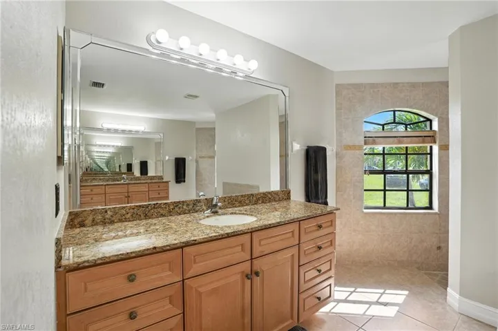 Bathroom with vanity, a walk in shower, and tile patterned floors