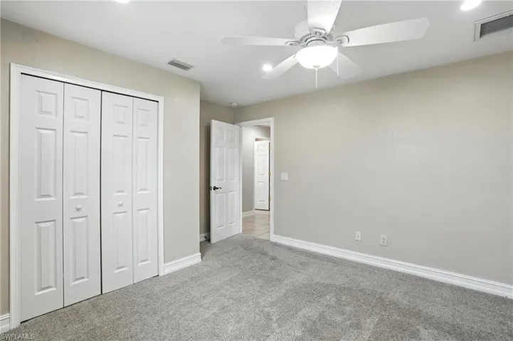 Unfurnished bedroom with carpet, a closet, and a ceiling fan